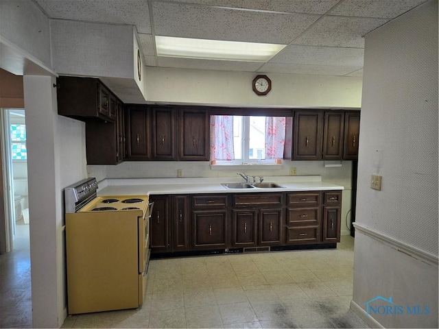 kitchen with dark brown cabinets, range with electric cooktop, a drop ceiling, and sink