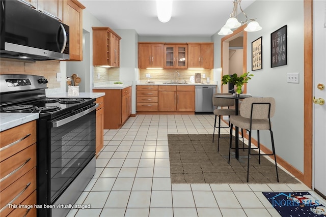 kitchen featuring sink, pendant lighting, decorative backsplash, light tile patterned flooring, and appliances with stainless steel finishes