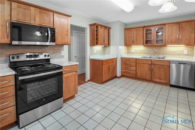 kitchen featuring tasteful backsplash, sink, light tile patterned floors, and appliances with stainless steel finishes