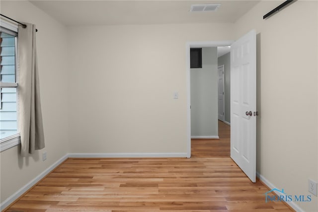 spare room with a barn door and light hardwood / wood-style floors