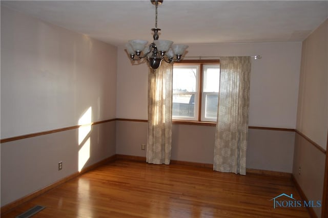 empty room with a notable chandelier and light wood-type flooring