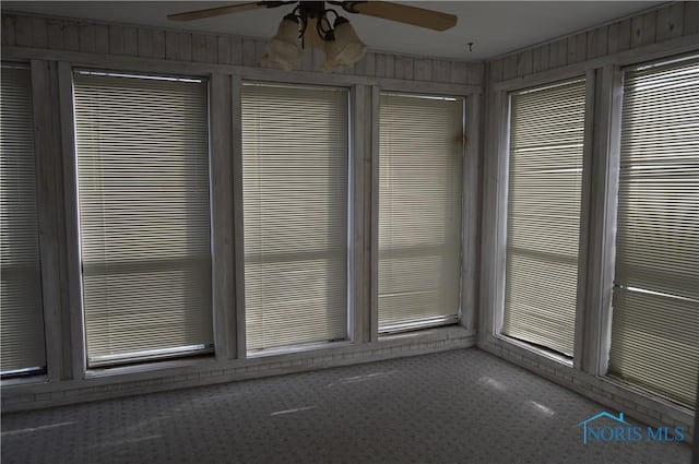 interior space featuring wooden walls and ceiling fan