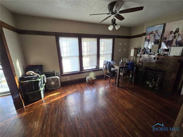 interior space with a textured ceiling, dark hardwood / wood-style flooring, and ceiling fan