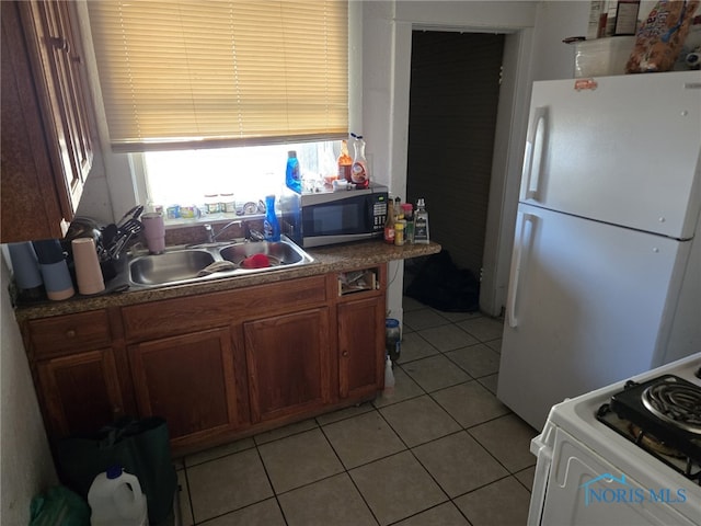 kitchen with white appliances, sink, and light tile patterned floors