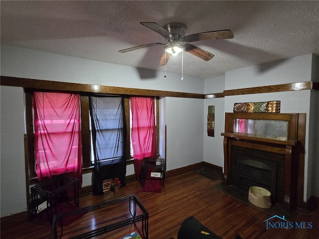 living room featuring ceiling fan, dark hardwood / wood-style flooring, and a textured ceiling