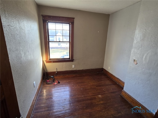 unfurnished room with dark hardwood / wood-style flooring