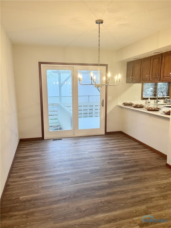 unfurnished dining area featuring a notable chandelier, dark hardwood / wood-style floors, and a wealth of natural light