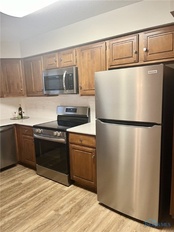 kitchen featuring decorative backsplash, light hardwood / wood-style floors, and appliances with stainless steel finishes