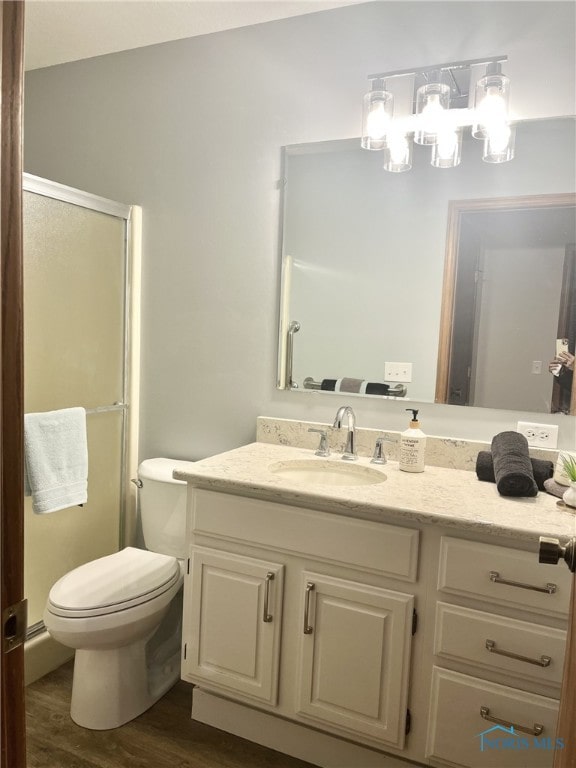 bathroom with wood-type flooring, vanity, toilet, and walk in shower