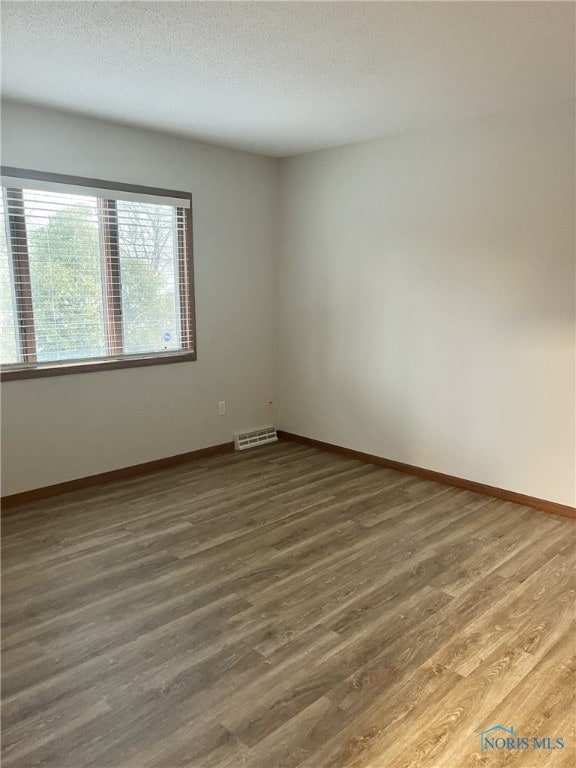 spare room with dark hardwood / wood-style flooring and a textured ceiling