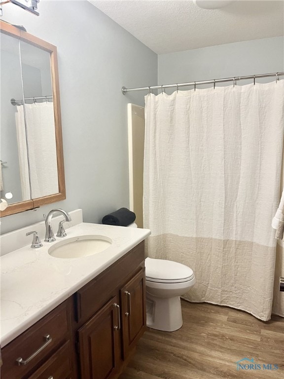 bathroom featuring hardwood / wood-style floors, vanity, toilet, and a textured ceiling