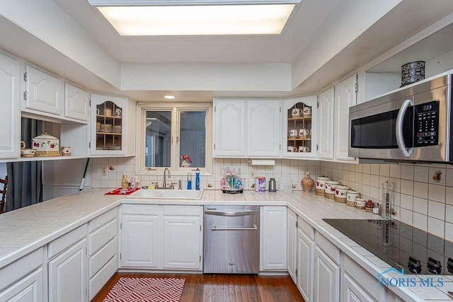 kitchen featuring appliances with stainless steel finishes, tasteful backsplash, sink, dark hardwood / wood-style floors, and white cabinetry