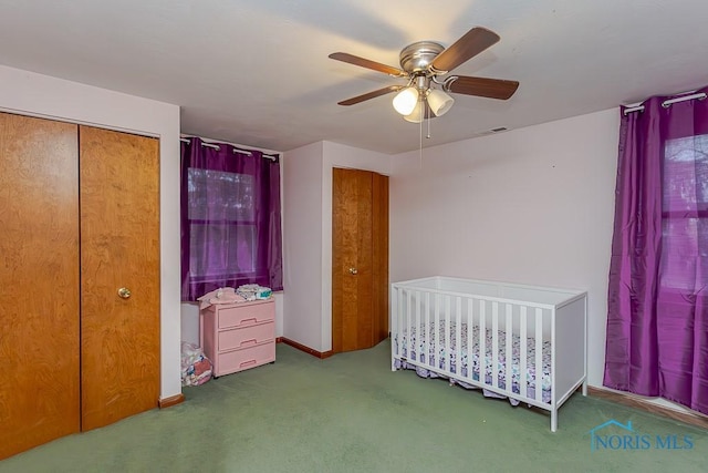 carpeted bedroom featuring ceiling fan, a closet, and a nursery area