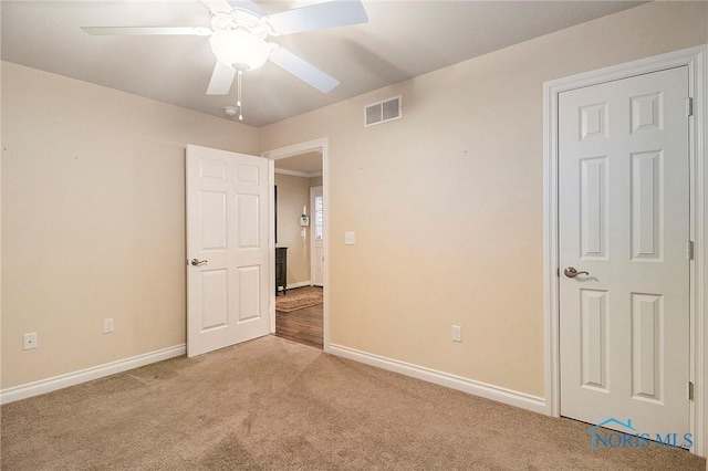 empty room featuring ceiling fan and light colored carpet