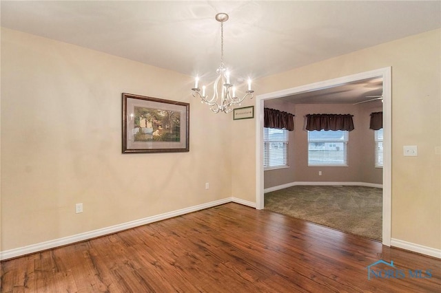 unfurnished room with hardwood / wood-style floors and an inviting chandelier