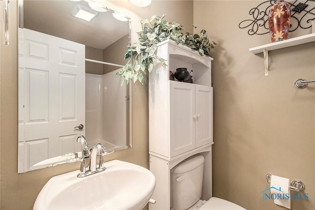 bathroom featuring a shower, toilet, and sink