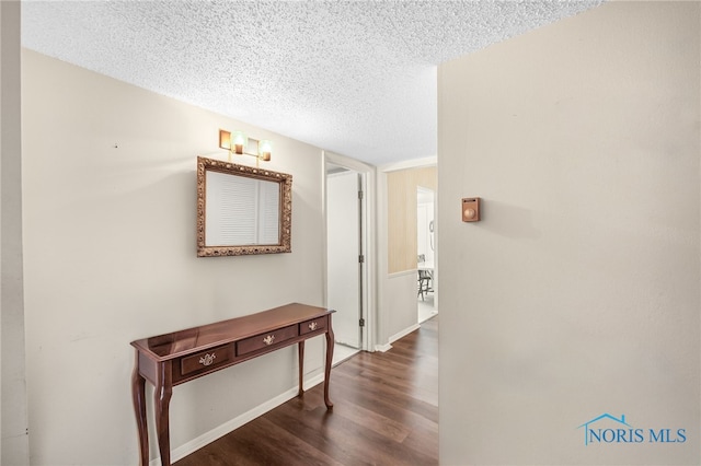 hallway with a textured ceiling and dark wood-type flooring