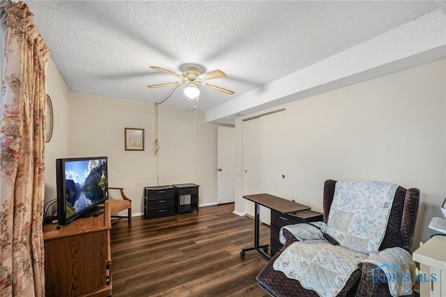 living area featuring ceiling fan, dark wood-type flooring, and a textured ceiling