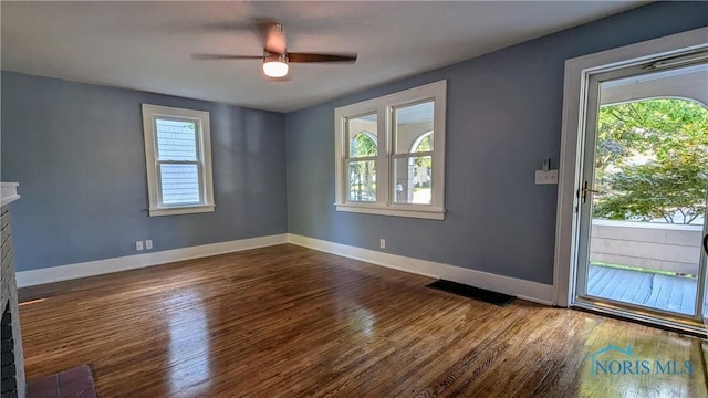 interior space with hardwood / wood-style flooring, ceiling fan, a stone fireplace, and a wealth of natural light