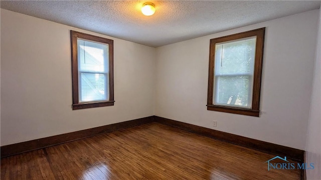 empty room with wood-type flooring and a textured ceiling