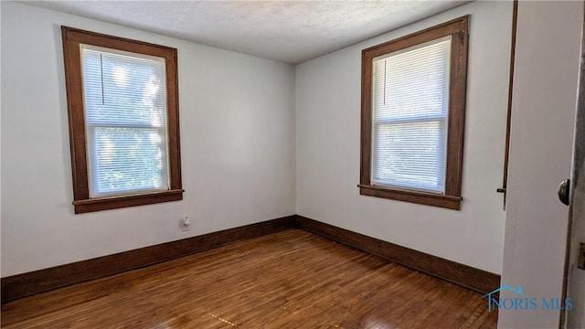 spare room featuring wood-type flooring, a textured ceiling, and plenty of natural light