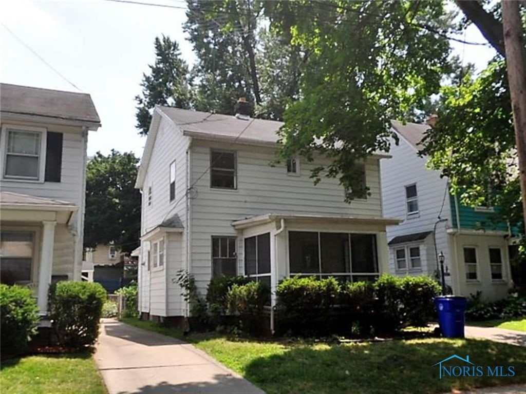 view of front of house with a front yard and a sunroom