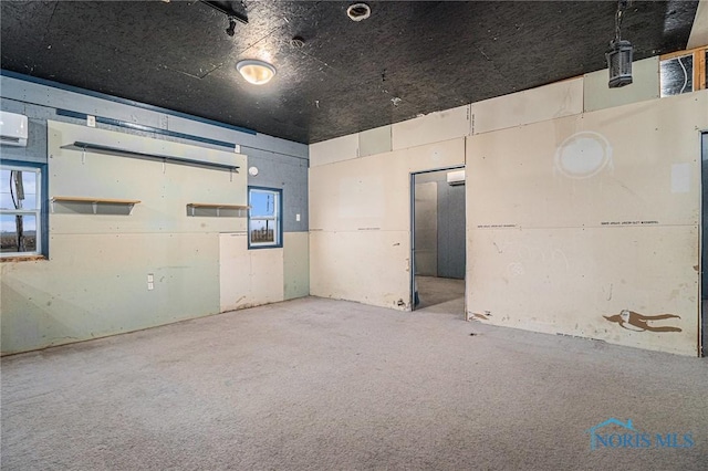 carpeted empty room featuring an AC wall unit