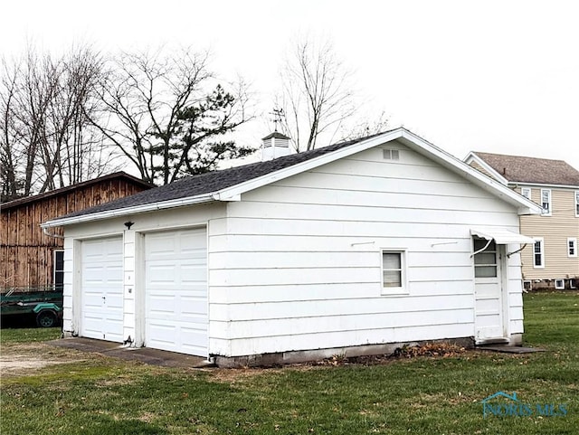 view of property exterior with a garage, a yard, and an outbuilding