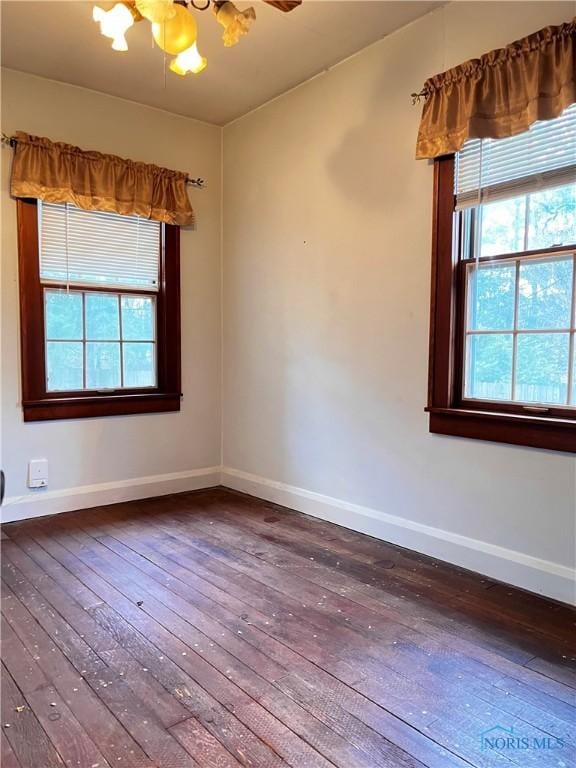 unfurnished room featuring a wealth of natural light, hardwood / wood-style floors, and an inviting chandelier