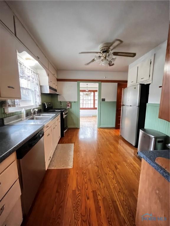 kitchen featuring white cabinets, sink, ceiling fan, light wood-type flooring, and appliances with stainless steel finishes