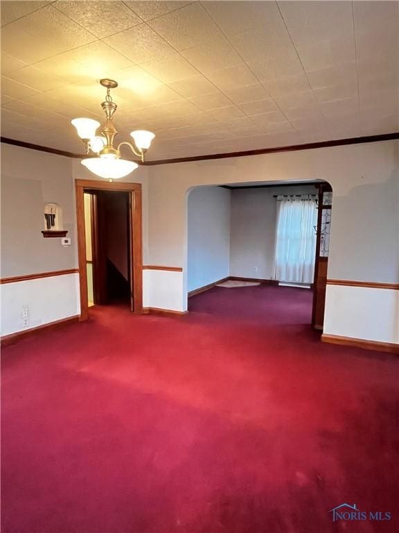 unfurnished room with crown molding, carpet, and a notable chandelier