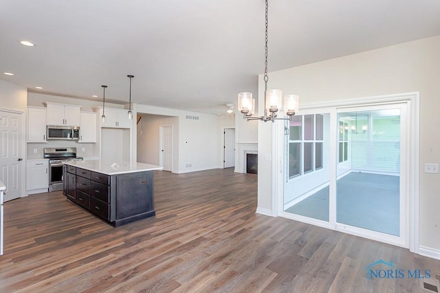 kitchen featuring appliances with stainless steel finishes, dark wood-type flooring, pendant lighting, a center island, and white cabinetry