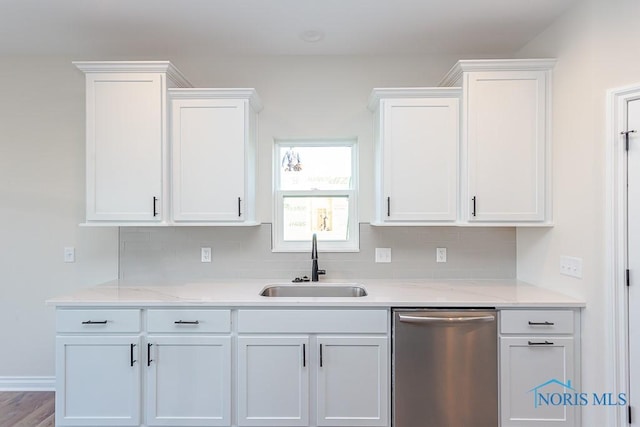 kitchen featuring stainless steel dishwasher, white cabinetry, sink, and tasteful backsplash