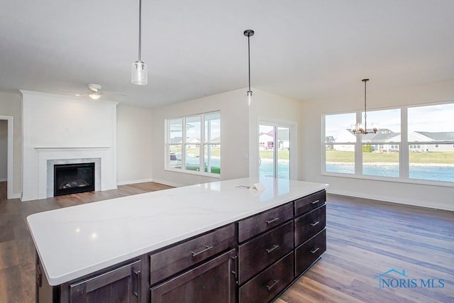 kitchen with hardwood / wood-style floors, ceiling fan with notable chandelier, and hanging light fixtures