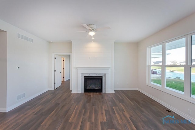 unfurnished living room with a large fireplace, dark hardwood / wood-style floors, and ceiling fan