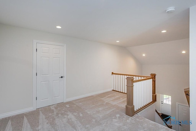 hallway featuring light colored carpet and vaulted ceiling