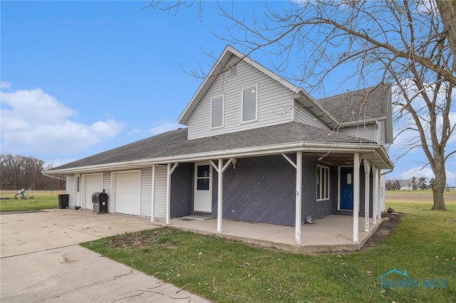 view of front of house featuring covered porch, a garage, and a front lawn