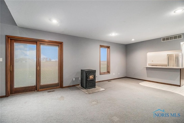 unfurnished living room with a wood stove and light carpet