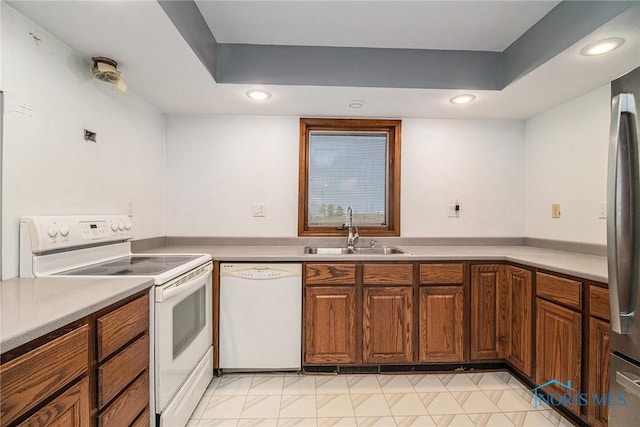 kitchen with a raised ceiling, white appliances, and sink