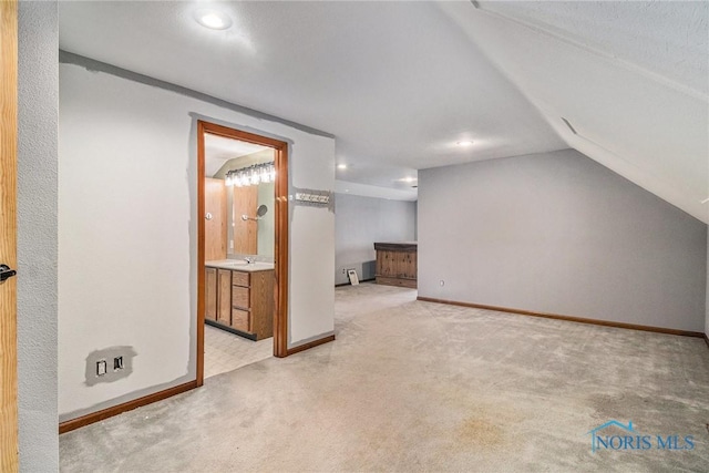 bonus room with a textured ceiling, light colored carpet, and vaulted ceiling