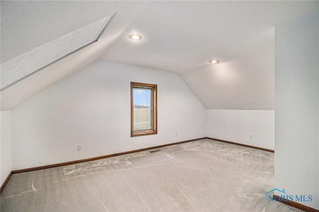 additional living space featuring carpet, lofted ceiling, and a textured ceiling