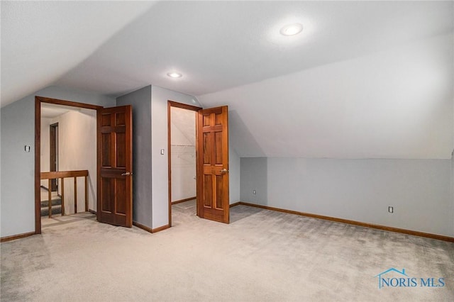 additional living space featuring light colored carpet and lofted ceiling