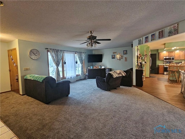 living room featuring ceiling fan, hardwood / wood-style floors, and a textured ceiling