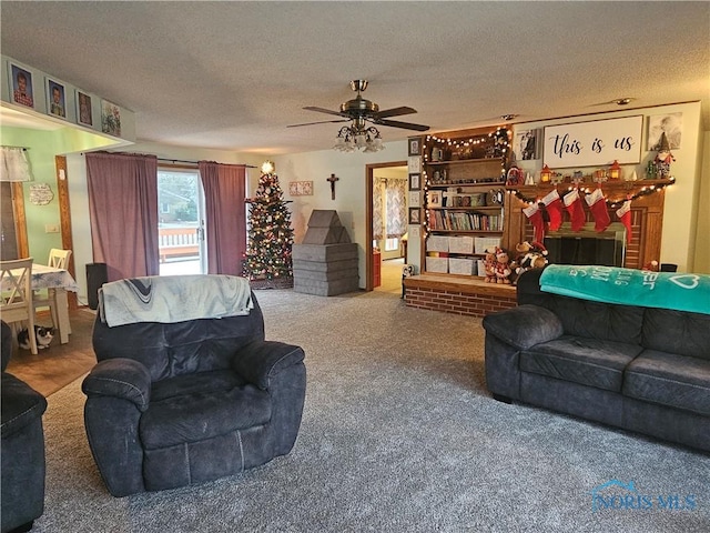 carpeted living room with ceiling fan, a fireplace, and a textured ceiling