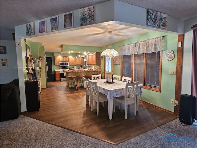 dining area featuring hardwood / wood-style flooring, a textured ceiling, and an inviting chandelier