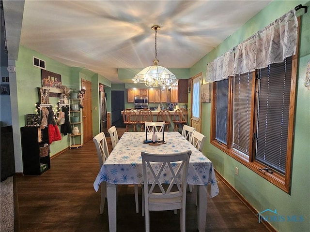 dining area with dark wood-type flooring and a notable chandelier