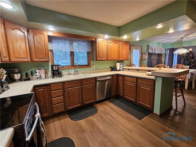 kitchen with sink, stainless steel dishwasher, dark hardwood / wood-style floors, kitchen peninsula, and a breakfast bar area