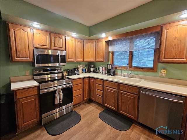 kitchen with appliances with stainless steel finishes, light hardwood / wood-style flooring, and sink