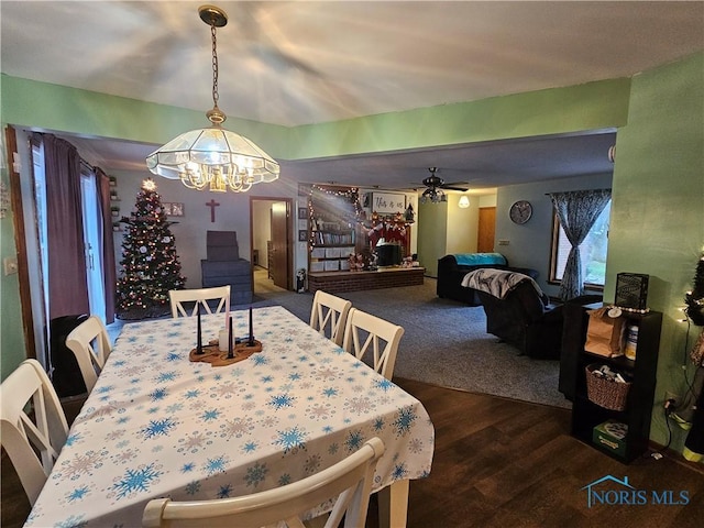 dining room with ceiling fan with notable chandelier and dark wood-type flooring