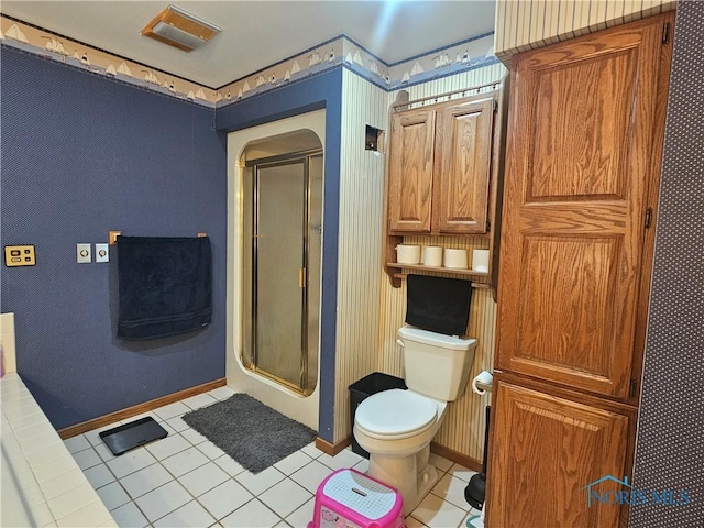 bathroom featuring tile patterned flooring, toilet, and a shower with door